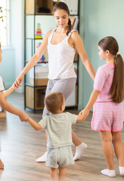Children participating in kindergarten dance activity, following teacher movements, fun and lively - they dance in a circle
