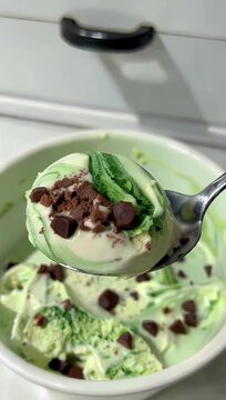 Ultra detailed 4K food b roll showing a metal scoop serving a perfect ball of creamy mint chocolate chip ice cream highlighting rich delicious dessert textures