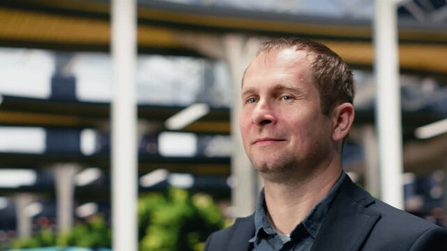 Close-up n upbeat businessman walking through the bus terminal with a calm expression, navigating the coach platform while traveling to the office on an intercity work journey.
