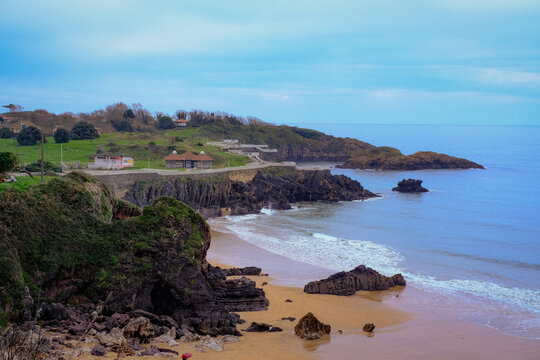 Scenic high-angle view of the rugged coastline in Perlora, Asturias, Spain, featuring a sandy beach, rocky formations