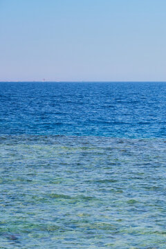 Crystal Clear Tropical Sea with Turquoise Shallow Water and Distant Parasail on Ocean Horizon