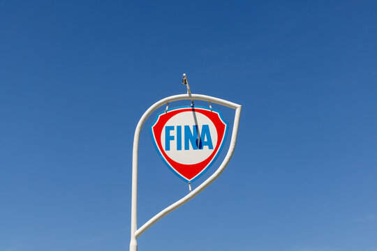 emblem of vintage Fina gas station in bright blue and red under blue sky.