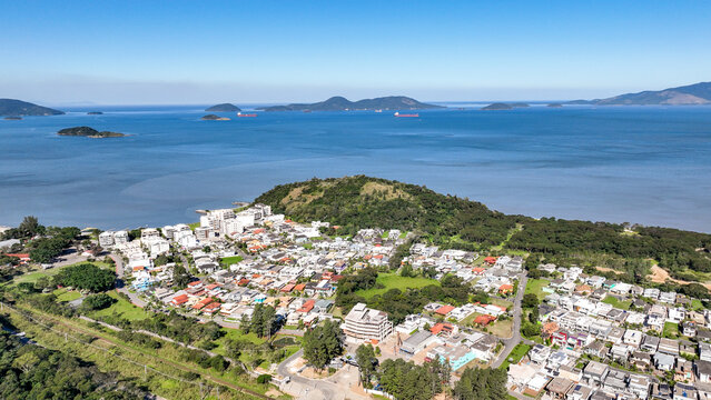 Reserva do Sahy, Condado, featuring modern residential houses nestled between lush green hills and the calm ocean waters in Mangaratiba, Rio de Janeiro, Brazil. Aerial view.