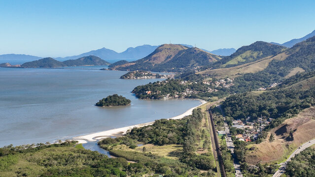 Reserva do Sahy, Condado, featuring modern residential houses nestled between lush green hills and the calm ocean waters in Mangaratiba, Rio de Janeiro, Brazil. Aerial view.