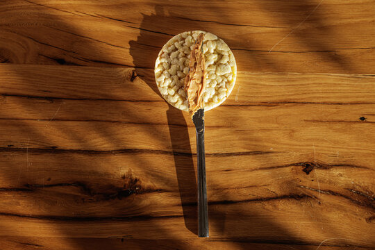 Peanut Butter Spread On Round Rice Cake Over Wooden Table