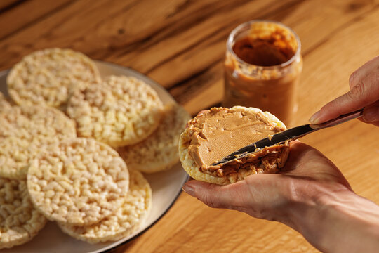 Hand Spreading Peanut Butter on Crunchy Rice Cake Snack