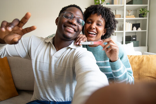 Happy couple sharing pregnancy test result on video call