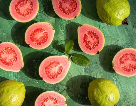 Fresh guavas arranged on a green textured surface, highlighting their vibrant