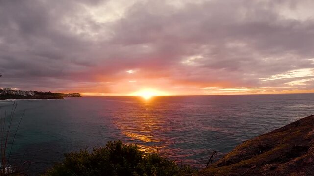 Timelapse video of a colourful burning sunrise over the ocean at Bronte Beach, Sydney, Australia.