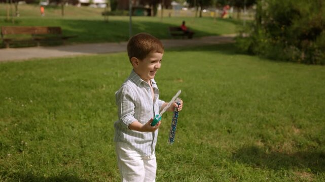 Happy little boy blowing soap bubbles in the park