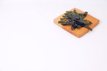 Crunchy seaweed rests on a wooden board. Clean, minimalist background highlights texture and color. Ideal for healthy food, wellness, or Asian cuisine visuals. No people, no animals, no plants © Nurma