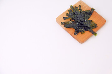 Crunchy seaweed rests on a wooden board. Clean, minimalist background highlights texture and color. Ideal for healthy food, wellness, or Asian cuisine visuals. No people, no animals, no plants © Nurma