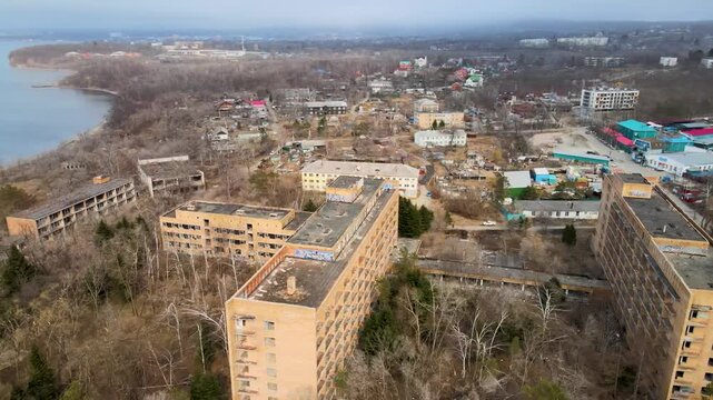 Aerial drone footage of the abandoned Sadgorod Mud Treatment Clinic near Vladivostok, Russia, showing old buildings, overgrown grounds, and the sea. The abandoned Soviet-era complex.