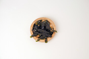 Dried seaweed rests in a simple wooden bowl. Minimalist background highlights texture and natural color. Clean white surface emphasizes products organic quality. Ideal for health, wellness © Nurma