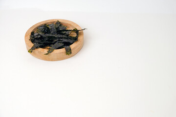 Dried seaweed rests in a simple wooden bowl. Minimalist background highlights texture and natural color. Clean white surface emphasizes products organic quality. Ideal for health, wellness © Nurma