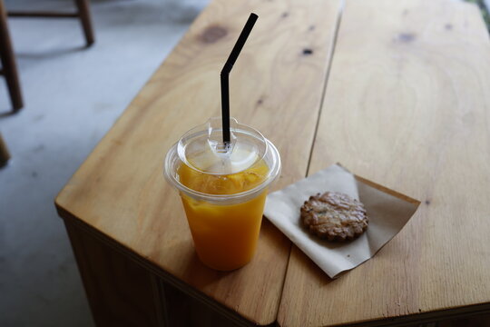 カフェのおやつ。オレンジジュースとクッキー。木製テーブル