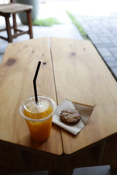 カフェのおやつ。オレンジジュースとクッキー。木製テーブル
