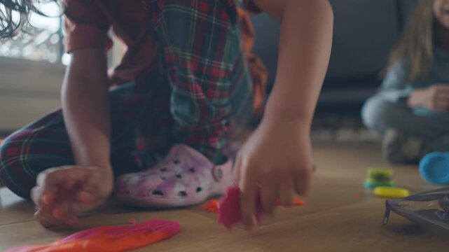 Boy pulling and stretching colourful modelling clay with a rolling pin nearby