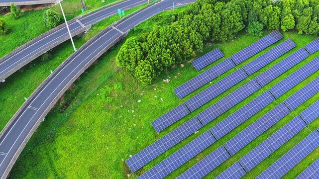 Top down drone view orbiting solar panels beside a curved road