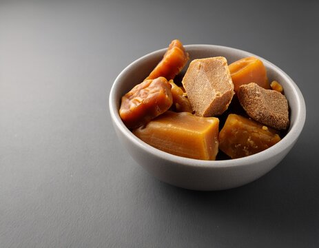 organic kithul jaggery and treacle sweeteners arranged in bowl with minimal gray background and room for text