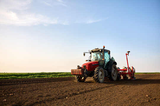 Farmer seeding field with tractor, preparing soil for new crop growth