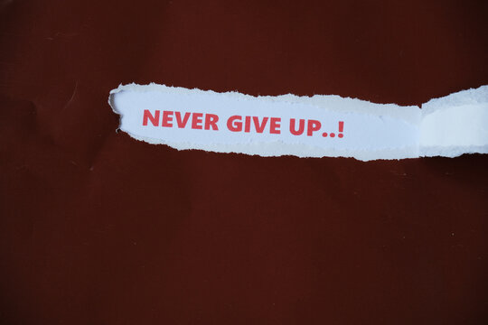 The words "NEVER GIVE UP" are written on the back of a torn piece of paper&mdash;a motivational message to keep going and not give up.

