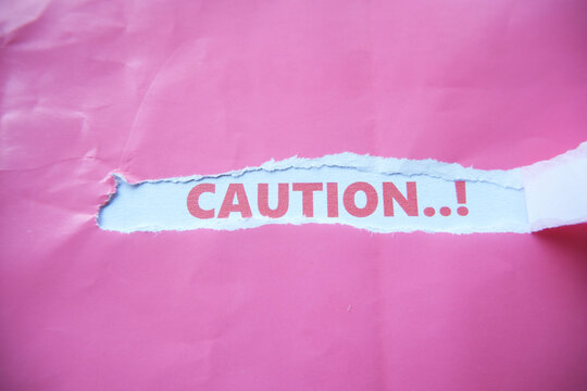 The word "CAUTION" is written on the back of a torn piece of paper. A warning sign for something dangerous.