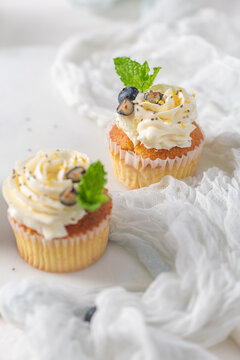 Cupcakes with cream frosting blueberry and mint leaves on a white surface