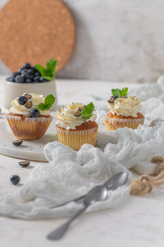 Cupcakes with cream frosting blueberry and mint leaves on a white surface