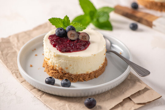 Mini cheesecake with blueberry topping and mint leaves on a white plate