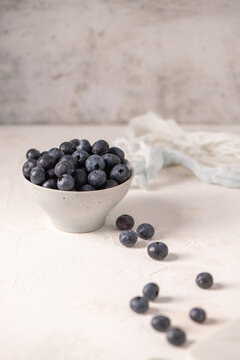Fresh blueberries in a ceramic bowl on a white textured surface