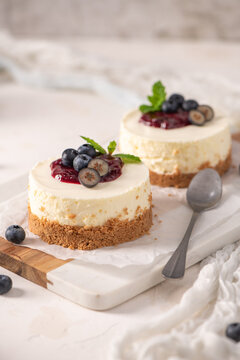 Mini cheesecakes with blueberry topping and mint leaves on a white board