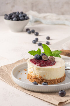 Mini cheesecake with blueberry topping and mint leaves on a white plate