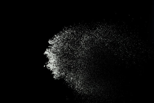 Fluffy White snow splash flying or throwing in mid air. Snowfall on Black background isolated. Snow dust element falling over dark night