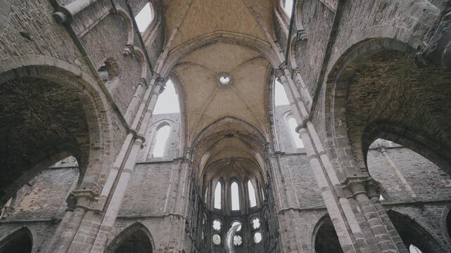Majestic gothic arches and towering stone walls of the ruined medieval Villers Abbey church in Belgium.