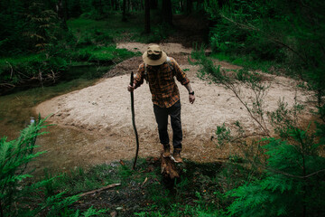Hiker with Wooden Walking Stick Stepping Across Forest Stream Sandbar © Maria Sap