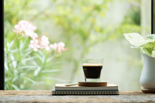 A cup of coffee on diary notebooks in front of window