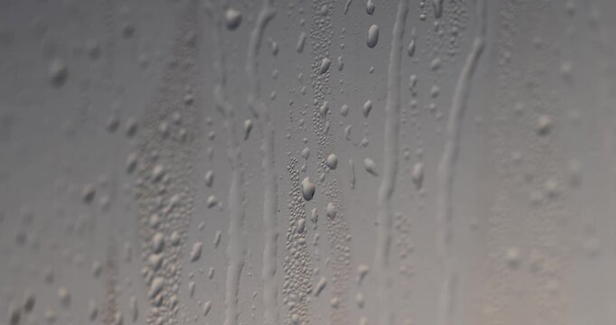   drops of water on the wet orange glass, drops of clear water cover the surface of the window due to the temperature difference outside and rain