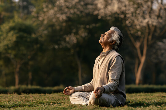 A wise breath comes from the elderly man as he practices pranayama on a serene morning
