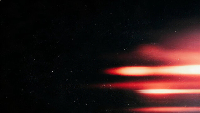 Horizontal red film light leak streaks with motion blur on black background