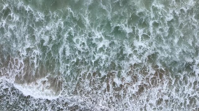 Ocean waves forming patterns. Waves hitting the sea edge. Sea surf with strong waves. Water waves moving at the sea.