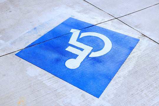 Wheelchair access symbol is painted on concrete surface in public location showing accessibility for individuals.