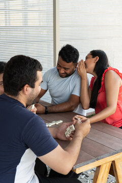Young adults playing dominoes at outdoor table