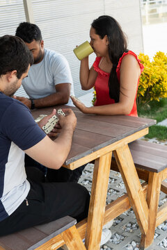 Young adults playing dominoes at outdoor table