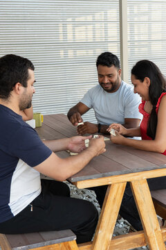 Diverse friends enjoying dominoes game at outdoor table