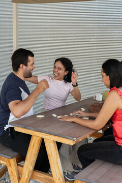 Young adult friends laughing playing dominoes outdoors