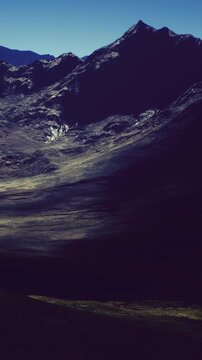 Breathtaking view of rugged mountains under a clear sky. Shadows dance across the valleys, revealing the beauty of nature at twilight. A serene moment of tranquility in the wilderness.