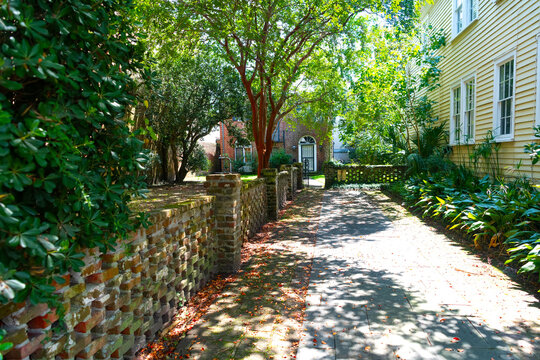 Shaded brick walkway passes old garden walls in Charleston's historic district.