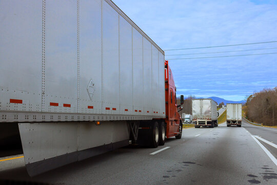 Several trucks drive along USA highway surrounded by mountains in North Carolina travelers distance.