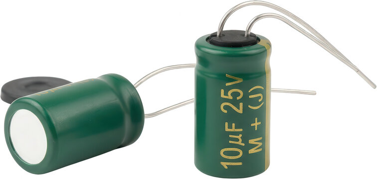 Two green electrolytic capacitors with metallic leads and gold lettering indicating capacitance and voltage values are positioned on a dark surface electronics electric component